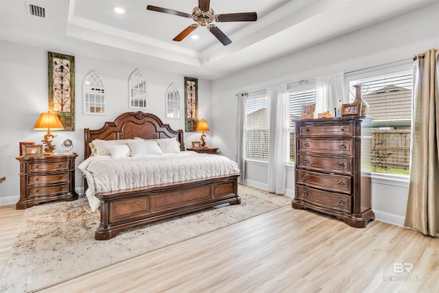 3905 Mercury Cir, Gulf Shores, AL 36542 - bedroom featuring multiple windows, visible vents, a tray ceiling, baseboards, and light wood-style floors