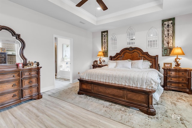 3905 Mercury Cir, Gulf Shores, AL 36542 - bedroom featuring a tray ceiling, light wood-type flooring, visible vents, baseboards, and ensuite bath