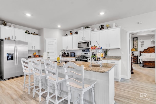 3905 Mercury Cir, Gulf Shores, AL 36542 - kitchen featuring a sink, a kitchen breakfast bar, white cabinets, light wood-type flooring, and appliances with stainless steel finishes