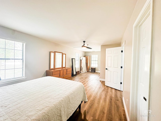 bedroom featuring ceiling fan, multiple windows, and hardwood / wood-style floors