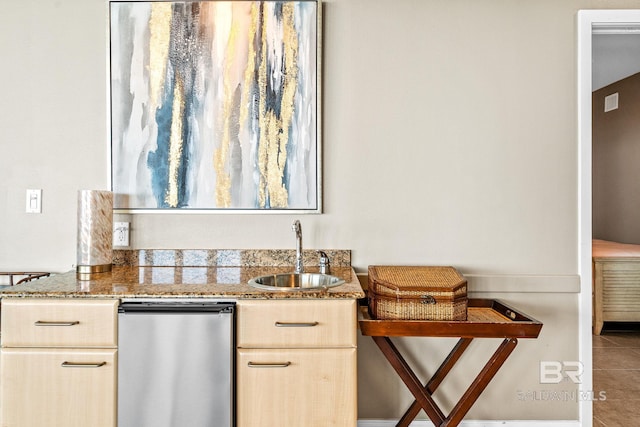 kitchen with stone counters, tile patterned flooring, a sink, and light brown cabinetry