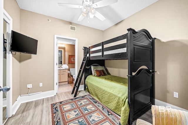 bedroom with light wood finished floors, visible vents, baseboards, a ceiling fan, and ensuite bath