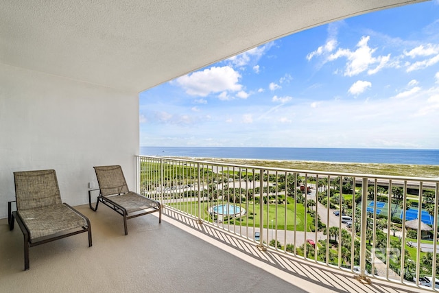 balcony with a water view and a view of the beach