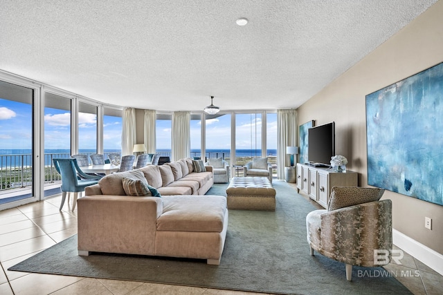 tiled living area with a wealth of natural light, expansive windows, a textured ceiling, and baseboards