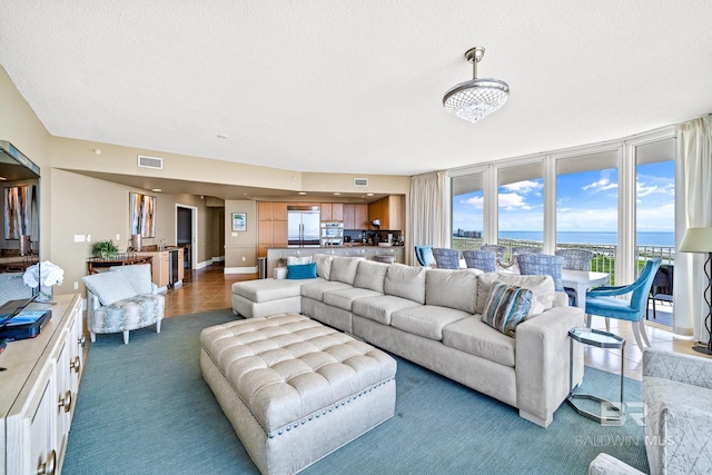 living room with baseboards, visible vents, a water view, a textured ceiling, and carpet floors