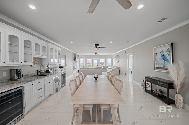 2420 Bienville Blvd, Dauphin Island, AL 36528 - dining area with beverage cooler, ceiling fan, light marble finish floors, ornamental molding, and recessed lighting