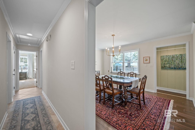 hall featuring light wood-type flooring, an inviting chandelier, baseboards, and ornamental molding