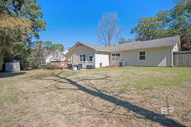 rear view of house featuring central AC, fence, and a lawn