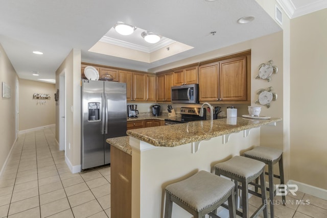 401 E Beach Blvd Unit 1704, Gulf Shores, AL 36542 - kitchen with appliances with stainless steel finishes, light tile patterned floors, a peninsula, brown cabinetry, and ornamental molding