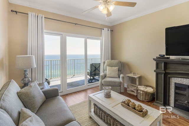 living room featuring ornamental molding, a fireplace, a water view, and light hardwood / wood-style floors