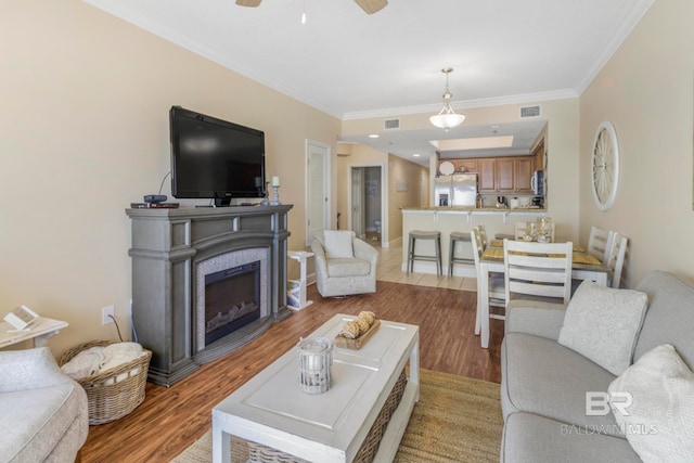 living room with ornamental molding, light hardwood / wood-style flooring, and ceiling fan