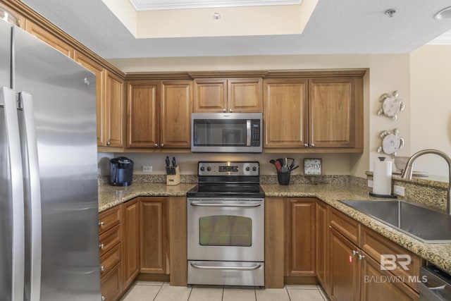 401 E Beach Blvd Unit 1704, Gulf Shores, AL 36542 - kitchen featuring appliances with stainless steel finishes, a sink, light tile patterned floors, and brown cabinets
