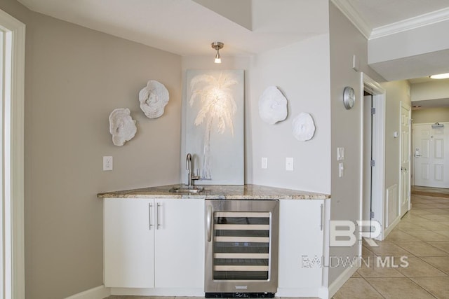 bar featuring crown molding, wine cooler, wet bar, a sink, and light tile patterned floors