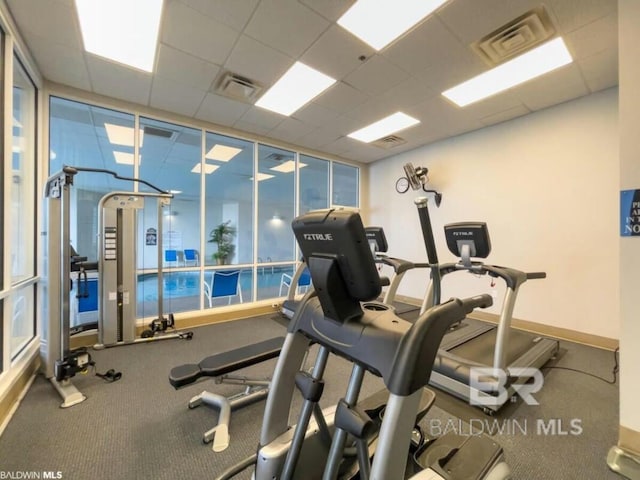 exercise room with floor to ceiling windows, visible vents, and a paneled ceiling