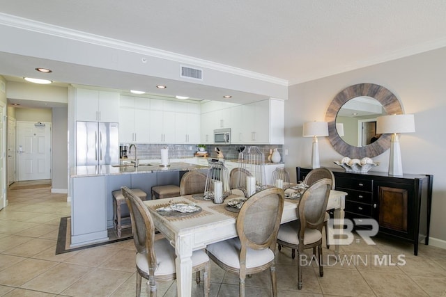 dining space with light tile patterned floors, ornamental molding, baseboards, and visible vents