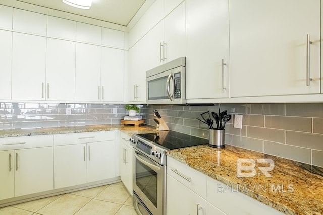 kitchen with light tile patterned flooring, appliances with stainless steel finishes, light stone counters, and decorative backsplash