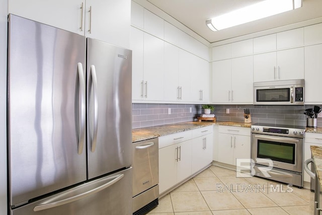 kitchen featuring stainless steel appliances, decorative backsplash, light tile patterned flooring, white cabinets, and light stone countertops