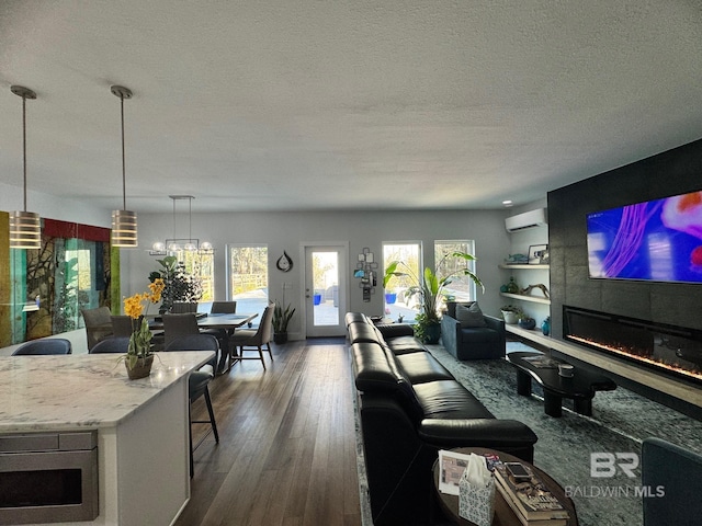 living room with a wall unit AC, a wealth of natural light, a fireplace, and dark wood-style flooring