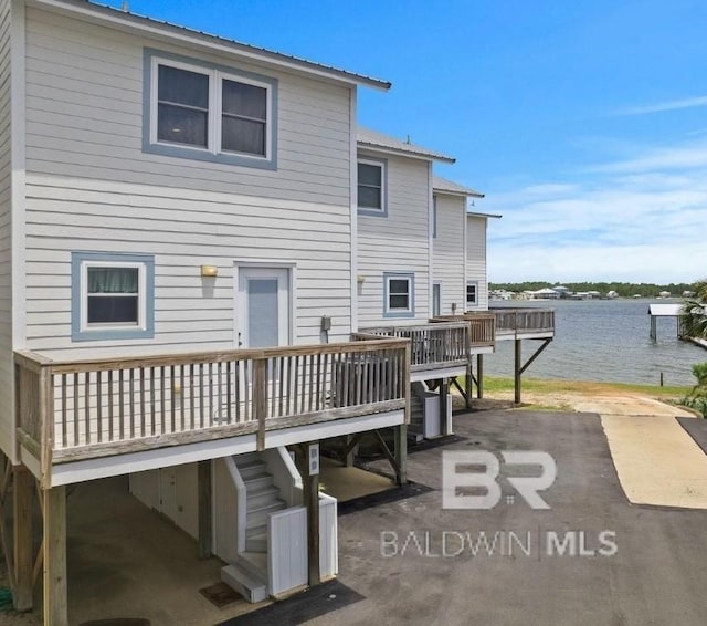 back of house with a deck with water view, metal roof, stairway, and a patio