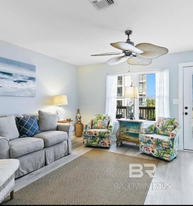 living room with ceiling fan, visible vents, and wood finished floors