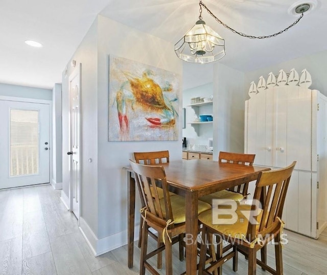 dining space featuring a notable chandelier, light wood-style flooring, and baseboards