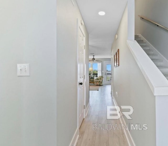 corridor with stairway, wood finished floors, and baseboards