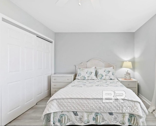 bedroom featuring ceiling fan, a closet, wood finished floors, and baseboards