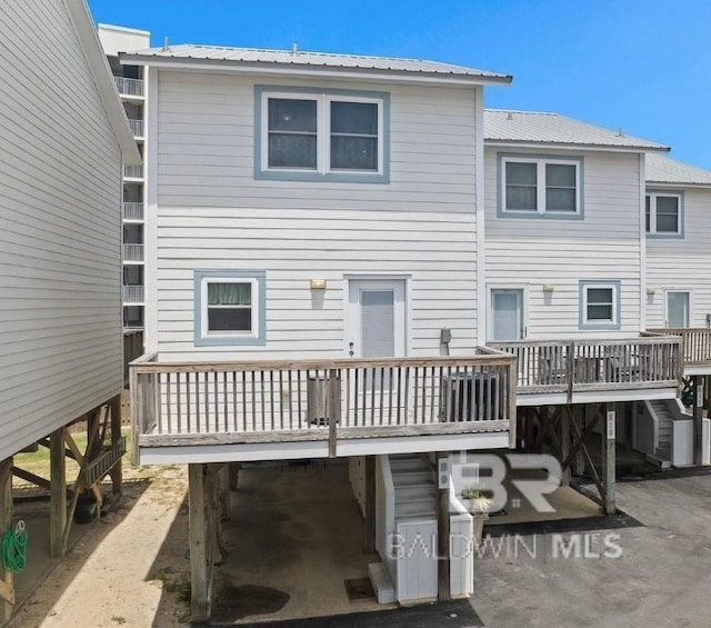 rear view of house featuring a deck, metal roof, and stairway