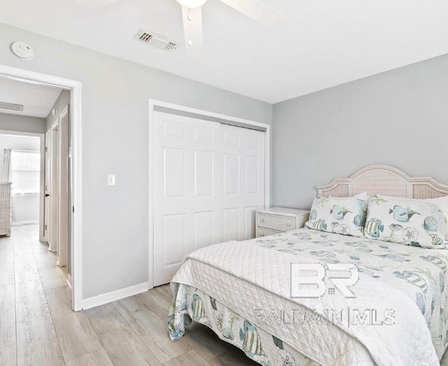 bedroom with baseboards, visible vents, a ceiling fan, light wood-style floors, and a closet