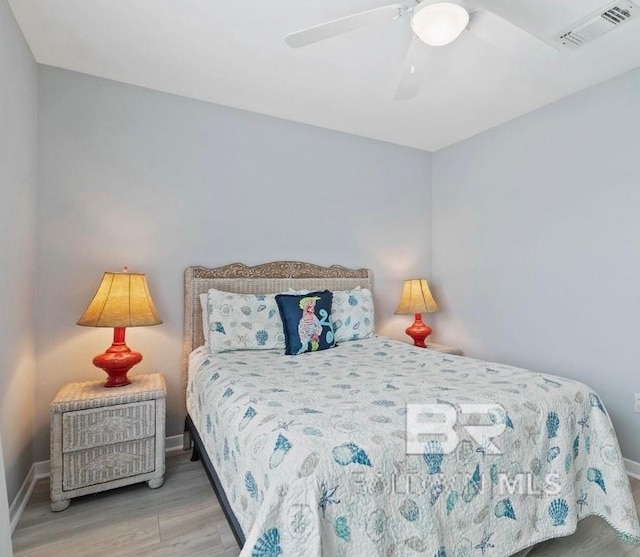 bedroom with a ceiling fan, baseboards, visible vents, and wood finished floors