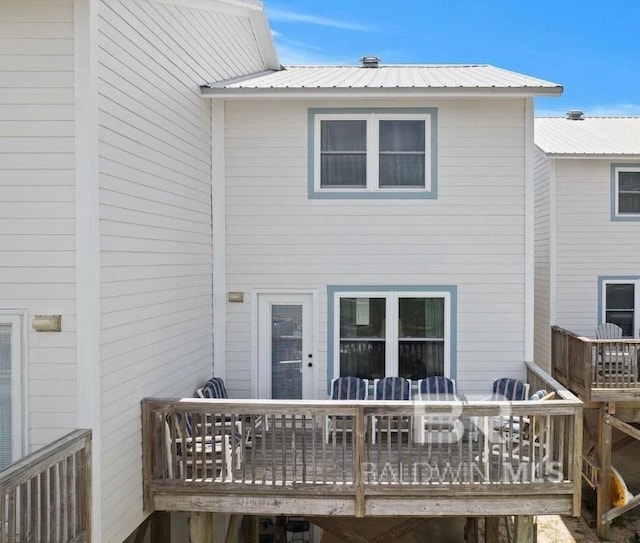 back of house with a deck, metal roof, and outdoor dining space