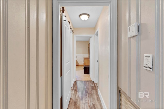 hall with a barn door and light hardwood / wood-style flooring