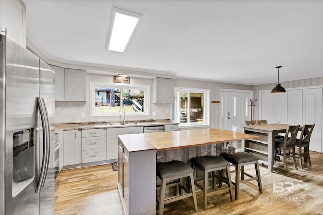 kitchen featuring decorative light fixtures, sink, wooden counters, a center island, and stainless steel appliances