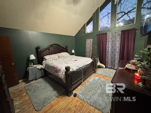 bedroom featuring lofted ceiling, baseboards, and wood finished floors