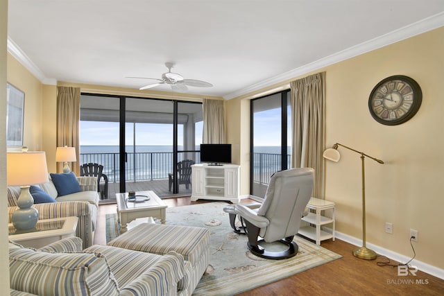 living room featuring ornamental molding, ceiling fan, baseboards, and wood finished floors