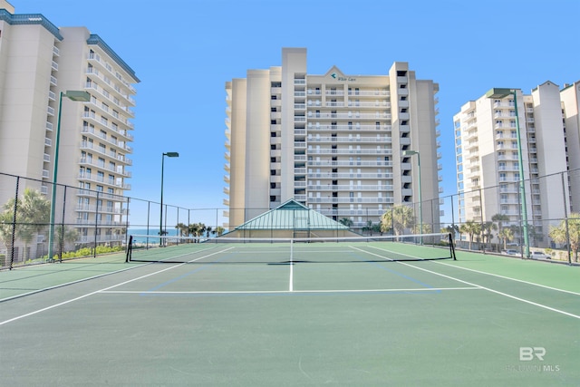 view of tennis court featuring community basketball court and fence