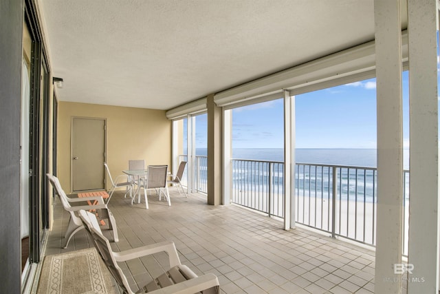 sunroom featuring a beach view and a water view