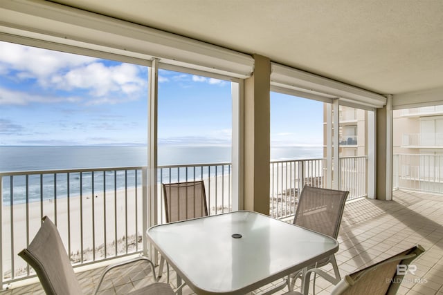 sunroom featuring a water view and a view of the beach