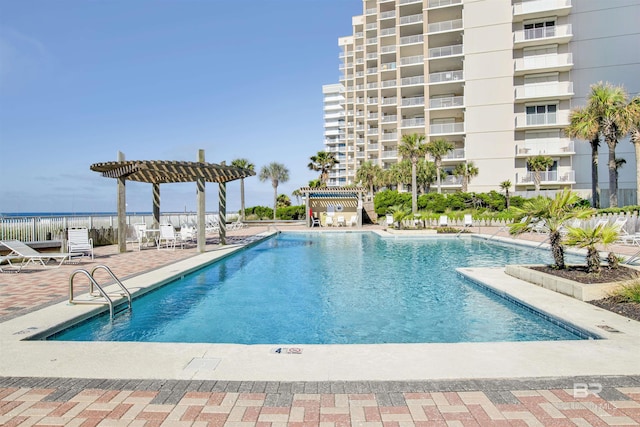 community pool with a water view, fence, a pergola, and a patio