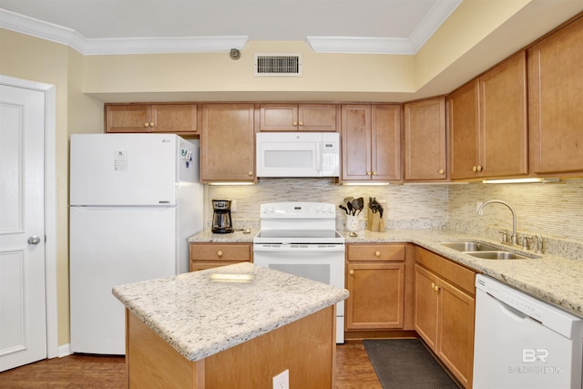 kitchen featuring white appliances, a sink, visible vents, ornamental molding, and a center island