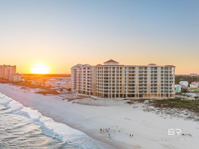 outdoor building at dusk featuring a water view and a beach view