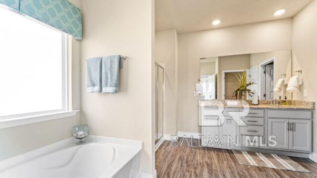 bathroom with vanity, shower with separate bathtub, and hardwood / wood-style floors