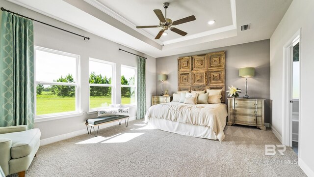 bedroom with ornamental molding, light carpet, ceiling fan, and a tray ceiling