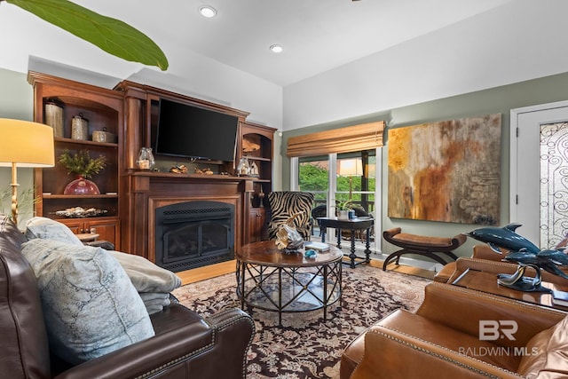 living room with recessed lighting, a fireplace with flush hearth, and wood finished floors