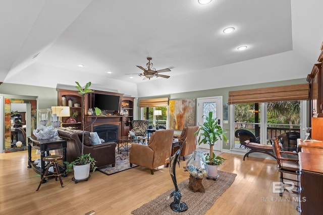 living room with a fireplace, a ceiling fan, recessed lighting, lofted ceiling, and light wood-type flooring