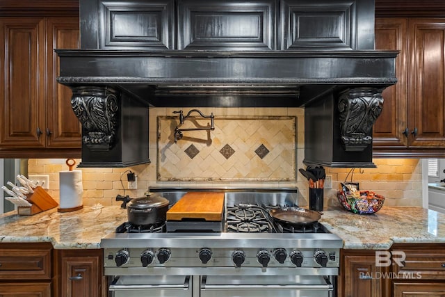 kitchen featuring light stone counters, high end stainless steel range, and backsplash