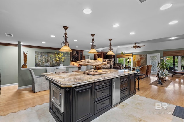 kitchen with visible vents, stainless steel microwave, open floor plan, dark cabinetry, and recessed lighting