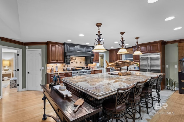 kitchen featuring crown molding, high quality appliances, light stone counters, recessed lighting, and a kitchen island