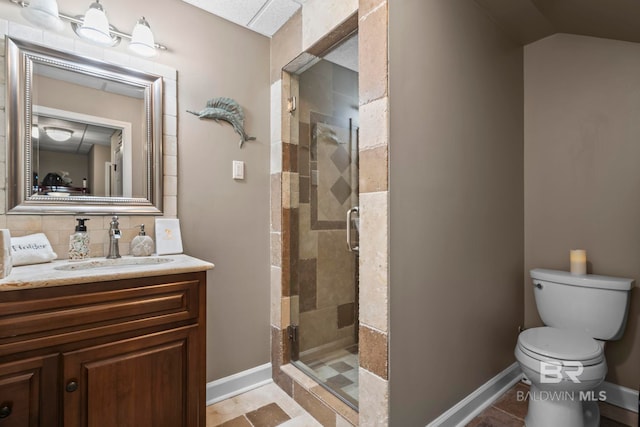 bathroom with vanity, toilet, baseboards, a shower stall, and backsplash