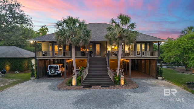 coastal inspired home featuring a porch, gravel driveway, stairway, and a carport